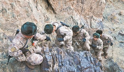 图②：官兵互帮互助，一同攀爬陡峭山坡。